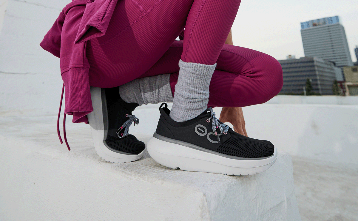 Women's OOmy Stride - White Black model crouched down outside | lifestyle