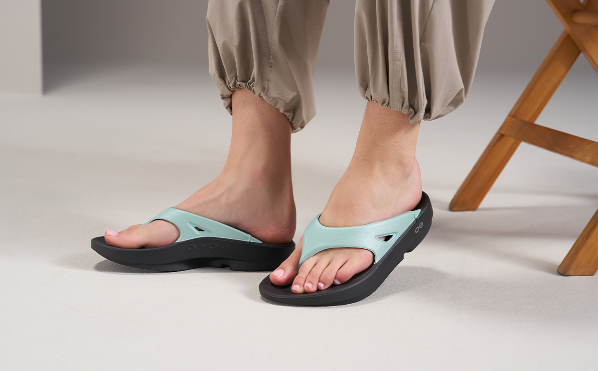 Person wearing light blue sandals with black soles on a neutral background | lifestyle