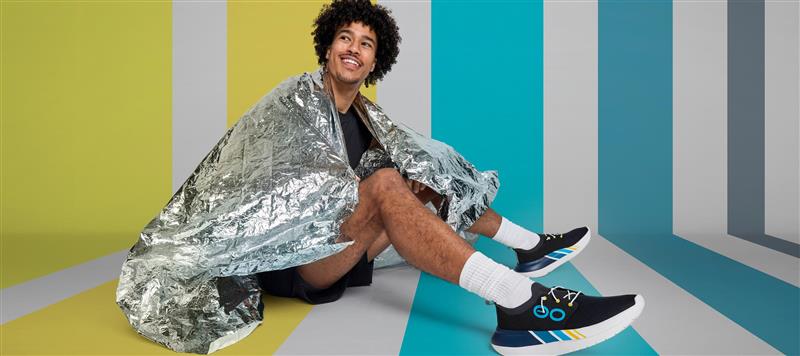 runner sitting down in studio wearing oomy stride limited edition 2025 with blue and yellow background