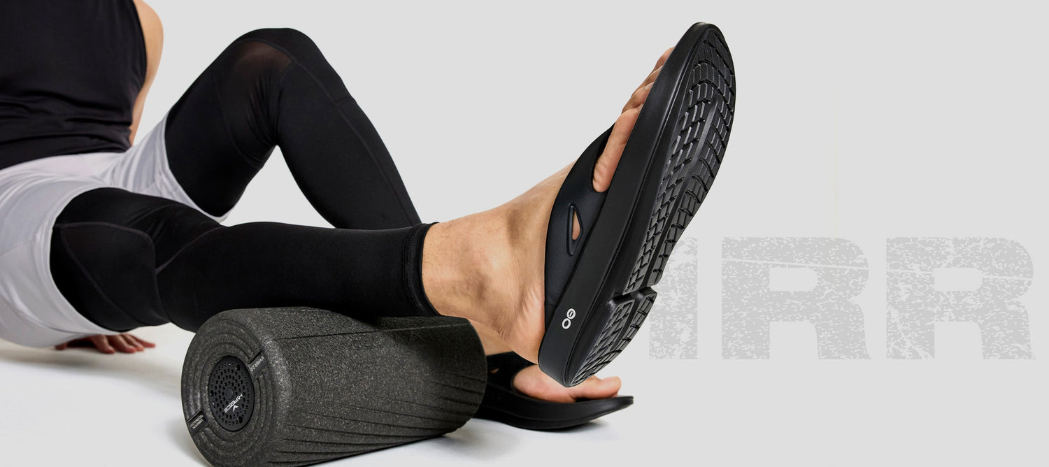 model sitting in studio using foam roller wearing ooriginal black