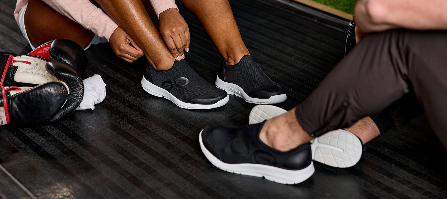 models sitting in gym studio wearing oomg sport white black