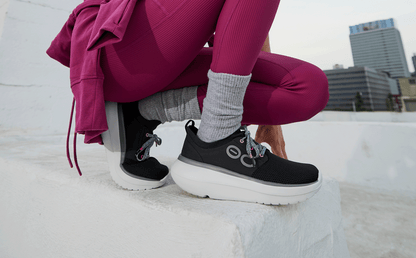 Women's OOmy Stride - White Black model crouched down outside | lifestyle