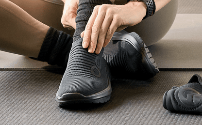 Women's OOmy Zen - Black model sitting adjusting shoe on workout mat | lifestyle