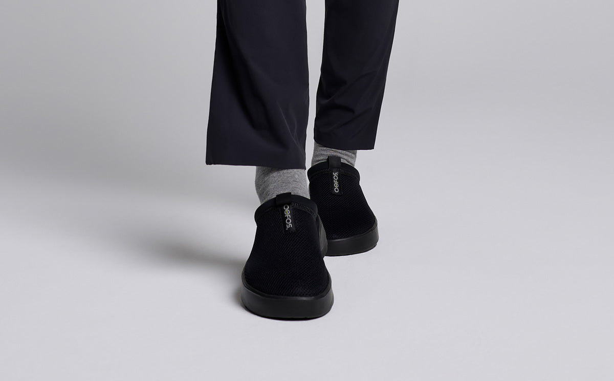 Women's OOcoozie Sport Mule - Black model walking in studio | lifestyle