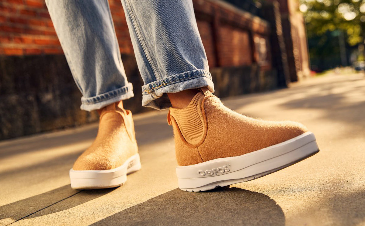 Person wearing tan ankle boots with white soles on a sidewalk | lifestyle