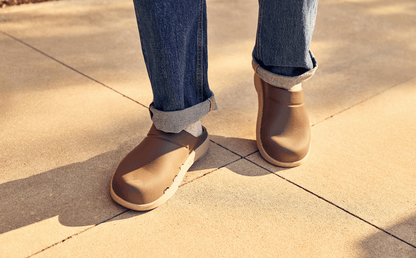 Brown shoes worn with rolled-up jeans on a pavement