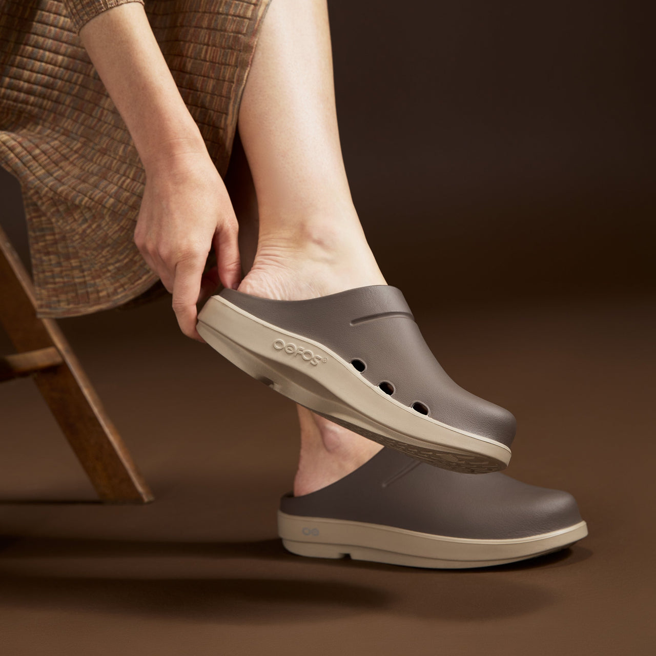 model sitting in studio with brown background wearing portobello clogs
