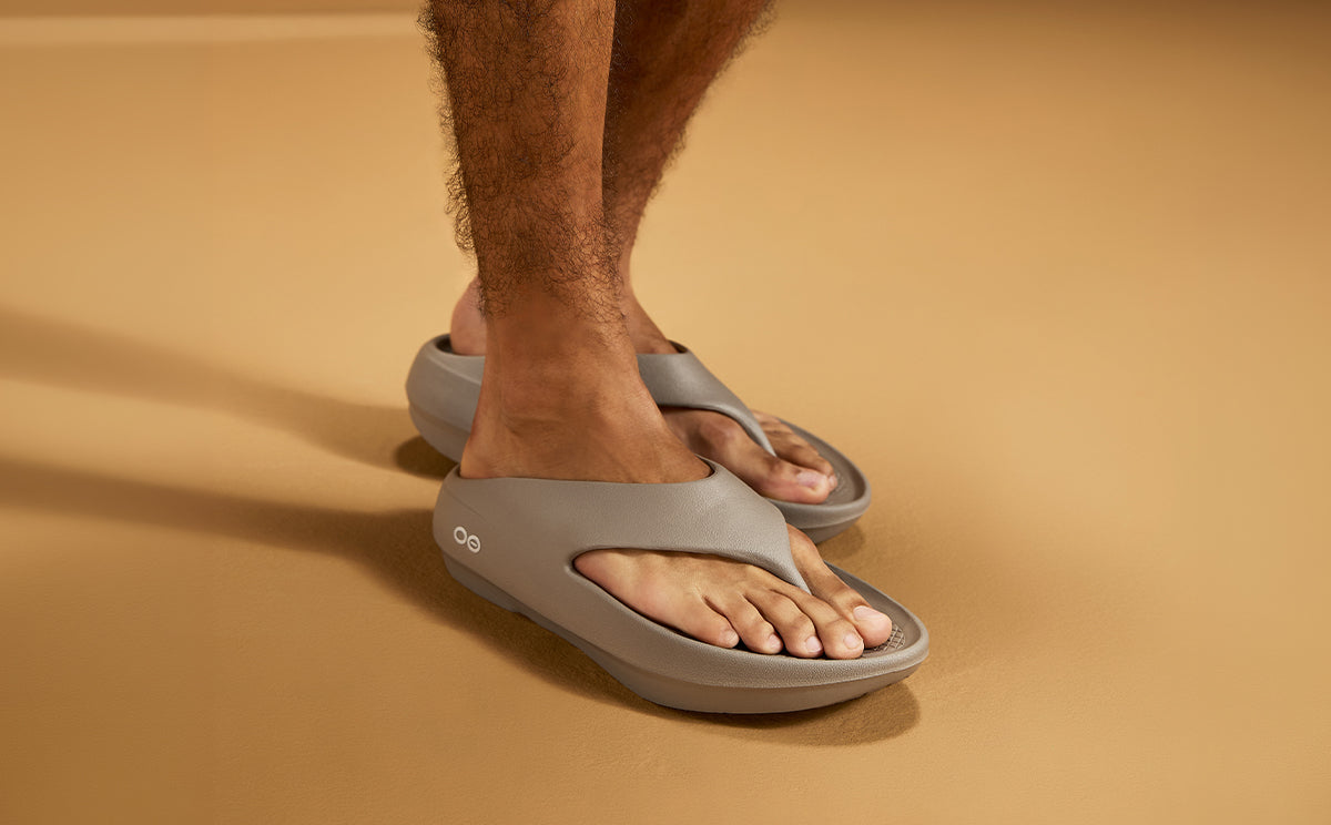 Person wearing driftwood sandals on a beige background | lifestyle