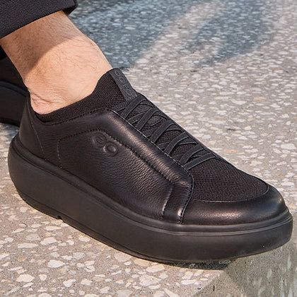 Black slip-on sneaker worn on a stone surface