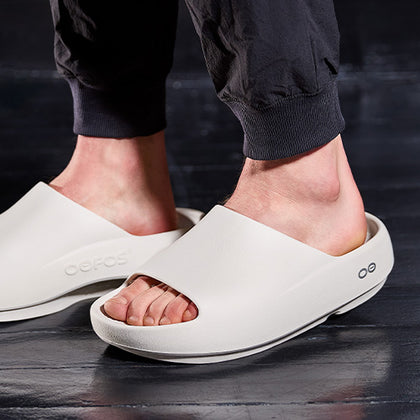 Chalk sandals worn by a person on a dark floor