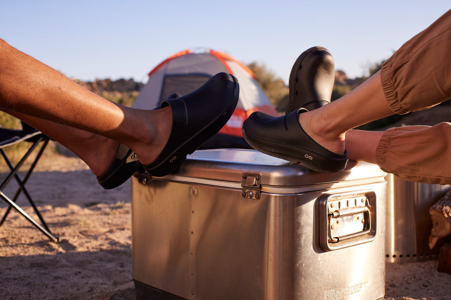 male and female models with feet on top on cooler at campsite | lifestyle
