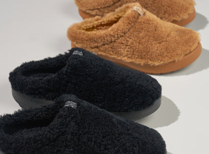 close up of women's sherpa slippers on white studio floor