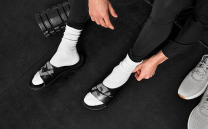 FJ X OOFOS Men's OOahh Sport Slide Sandal - Black top view of shoes on model in gym | lifestyle
