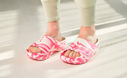 Pink and white tie-dye sandals worn by a person on a light wooden floor | lifestyle