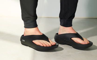 Person wearing black sandals on a light background | lifestyle