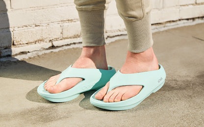 Person wearing light blue sandals on a concrete surface | lifestyle