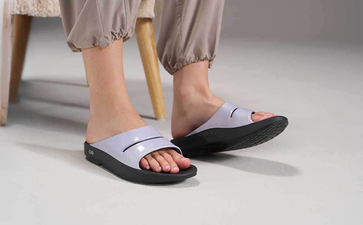 Person wearing black and lavender slides on a neutral background | lifestyle