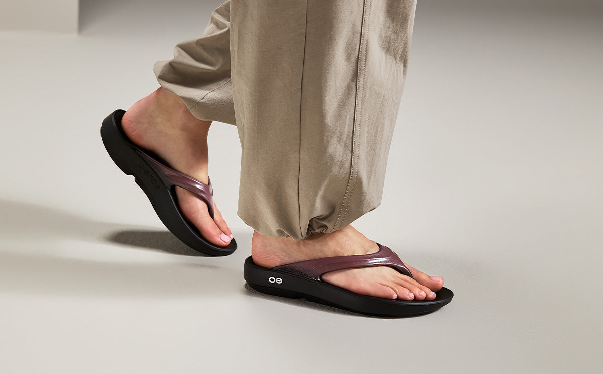 Person wearing black and rosewood sandals on a neutral background | lifestyle