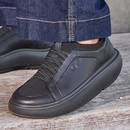 Black sneaker worn with blue jeans on a wooden floor