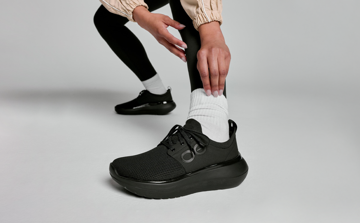 Women's OOmy Stride - Black model pulling up sock in studio | lifestyle