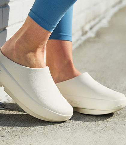 Chalk clogs worn by a person on a concrete surface