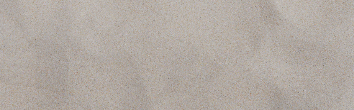 A close-up of a light beige textured surface with subtle tonal variation and fine grain.