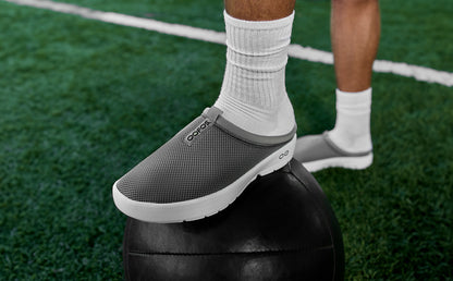 Men's OOcoozie Sport Mule - Slate model on fiend with foot on sports ball | lifestyle
