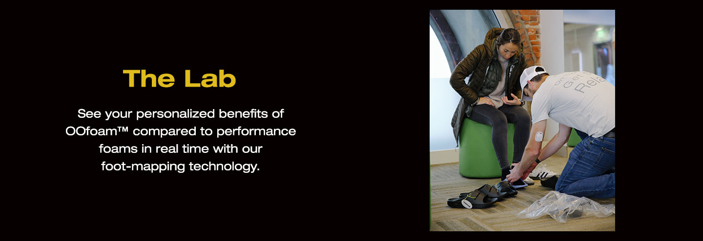 The Lab. See your personalized benefits of OOfoam™ compared to performance foams in real time with our foot-mapping technology. An image of an individual helping another individual try OOfoam™.