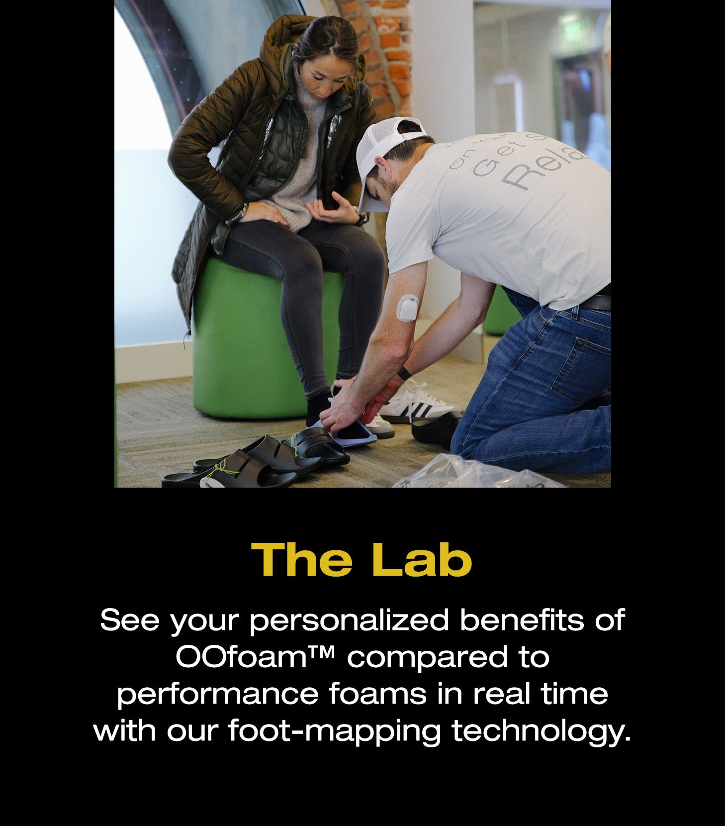 The Lab. See your personalized benefits of OOfoam™ compared to performance foams in real time with our foot-mapping technology. An image of an individual helping another individual try OOfoam™.